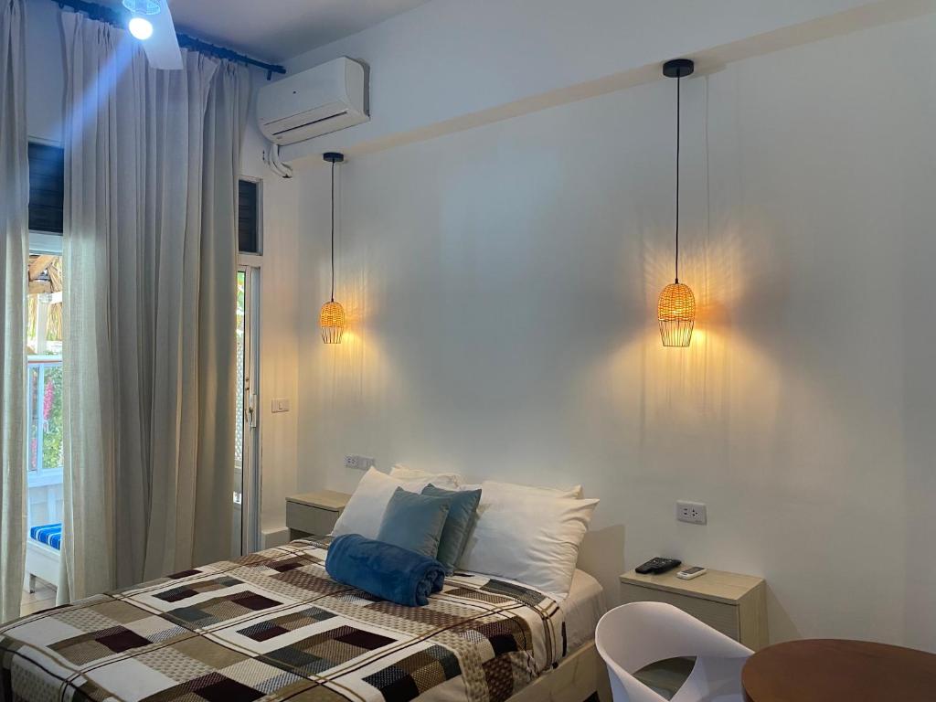 Apartamentos Magallanes Bayahibe في باياهيب: غرفة نوم بسرير واضاءين على الحائط