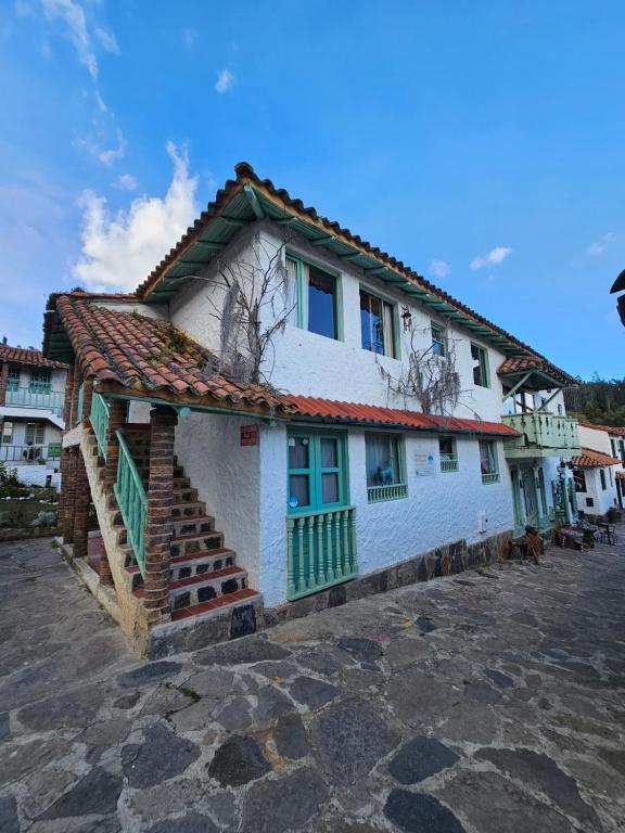 ein weißes Haus mit einem roten und grünen Dach in der Unterkunft PUEBLITO BOYACENSE - Hospedaje El Cocuy in Duitama
