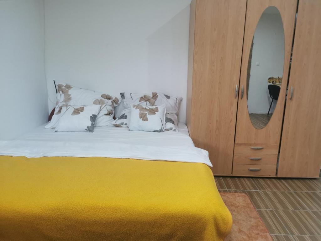 a bed with a yellow blanket next to a dresser at AG Studio Apartment in Gabčíkovo in Gabčíkovo