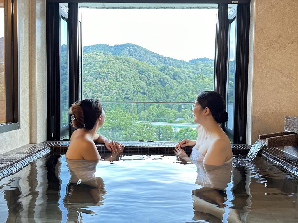 Dos mujeres sentadas en un jacuzzi con vistas en Garland Court Usami Private Hot Spring Condominium Hotel, en Ito