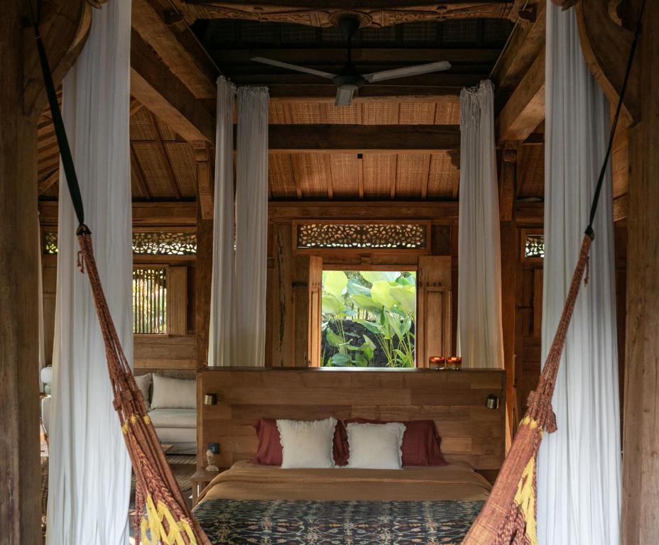 a hammock in a room with a window at Joglo Manis Villa in Ubud