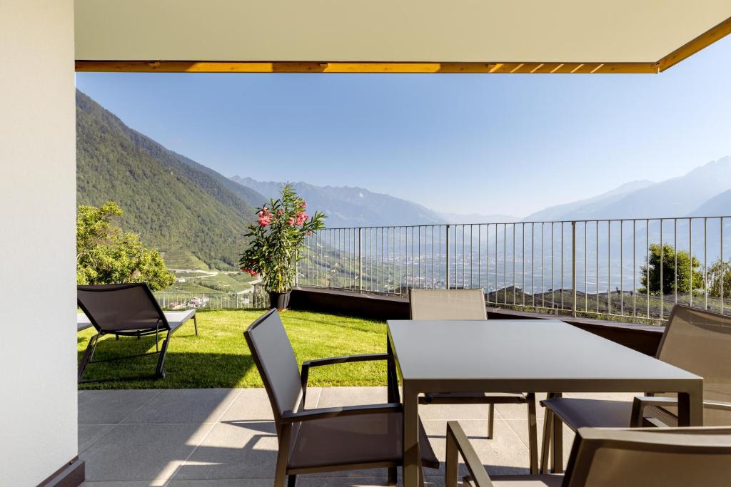 una mesa y sillas en un balcón con montañas en Appartments Jaufenblick en Lana