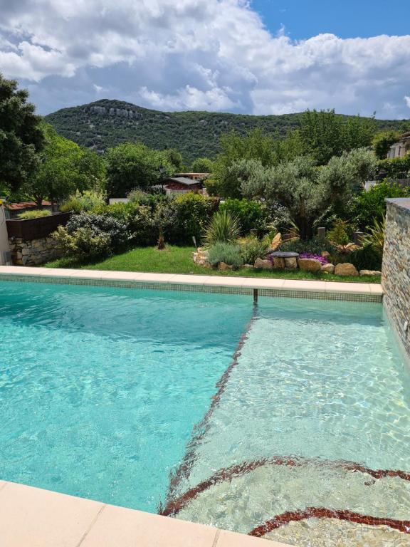 a blue swimming pool with a mountain in the background at Gîte spa la parenthèse in Sauve