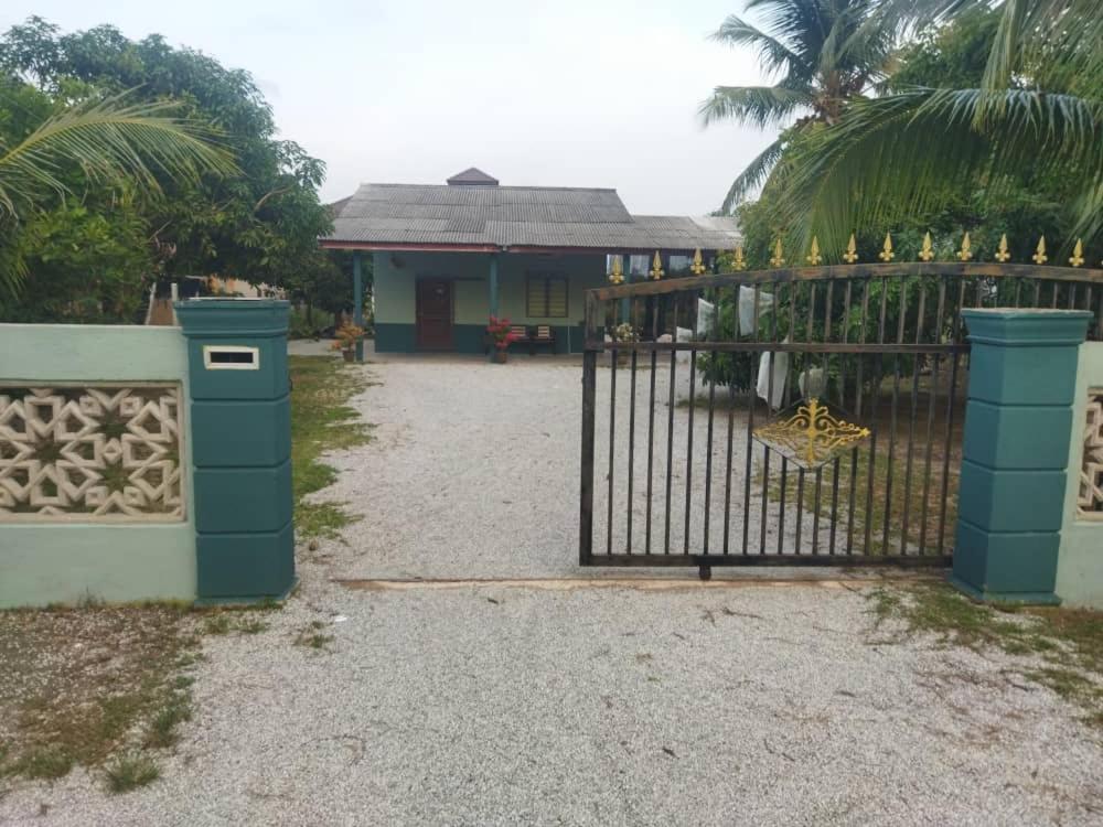 a gate in front of a house with a palm tree at Ustazah Homestay in Kampong Ru Sepuloh