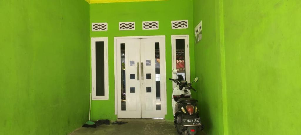 a green room with a motorcycle in front of a green wall at Alesya Homestay 
