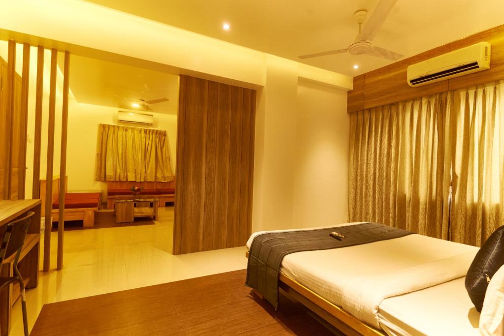 1 dormitorio con 1 cama y sala de estar en Hotel Anand Heritage, en Shirdi