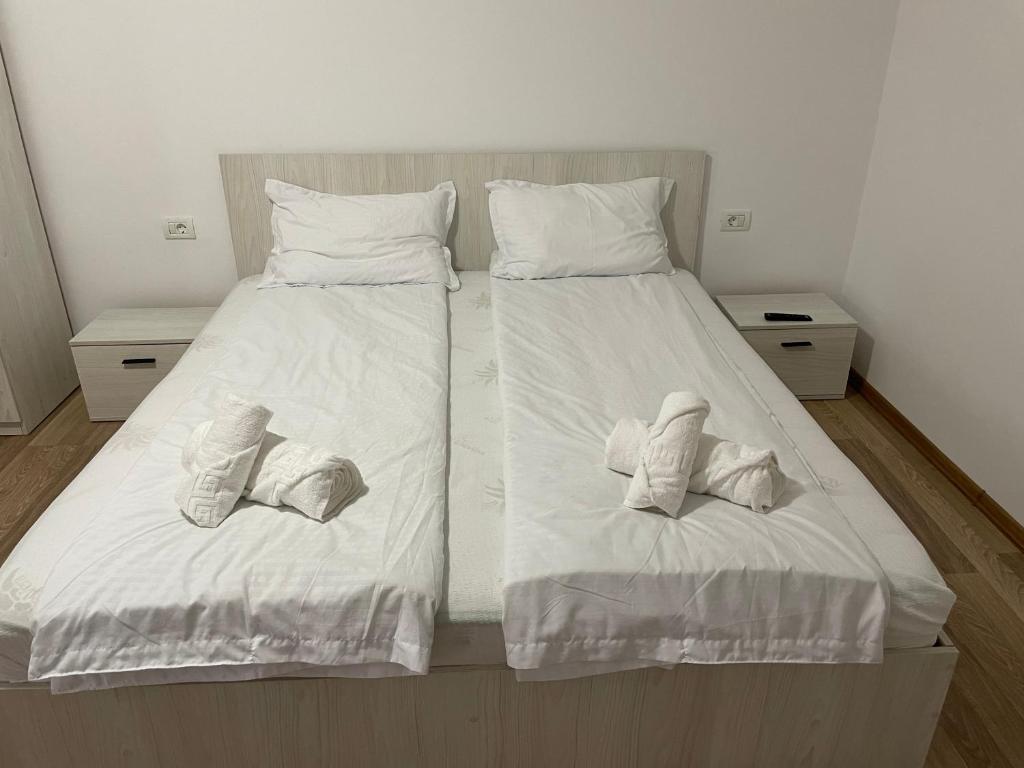 a bedroom with two beds with white sheets and towels at Casa Marko in Nădlac