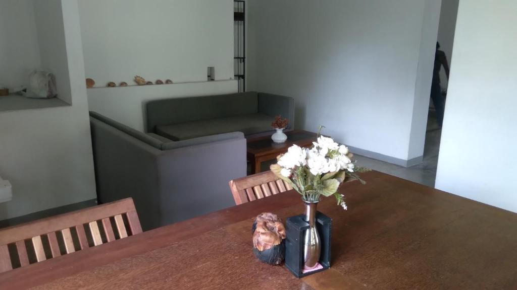 a vase of flowers on a table with a couch at Osu Lena Habaraduwa in Habaraduwa