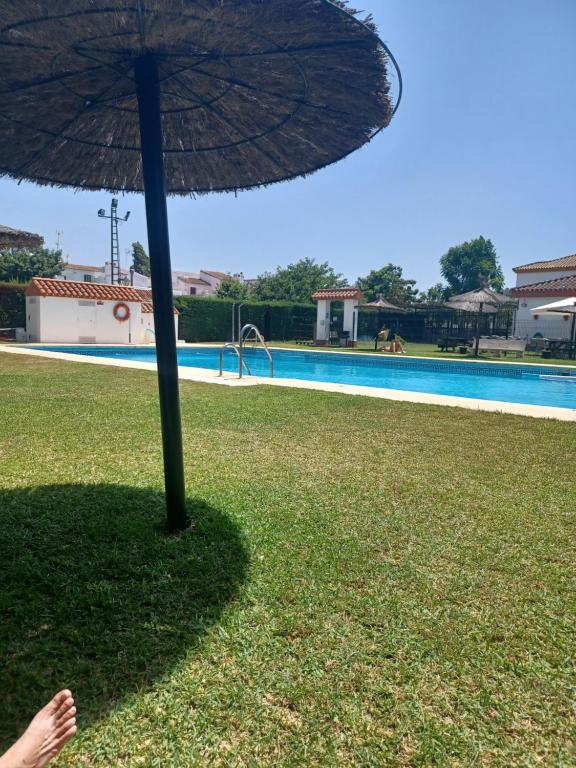 una persona parada bajo una sombrilla junto a una piscina en Private room ensuite with private balcony, en Chiclana de la Frontera