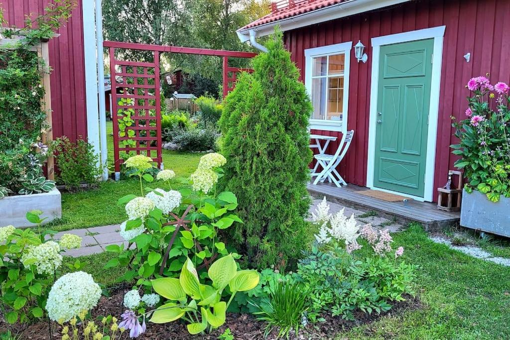 a red house with a green door and some flowers at Cabin located in a traditionally Swedish setting! in Umeå