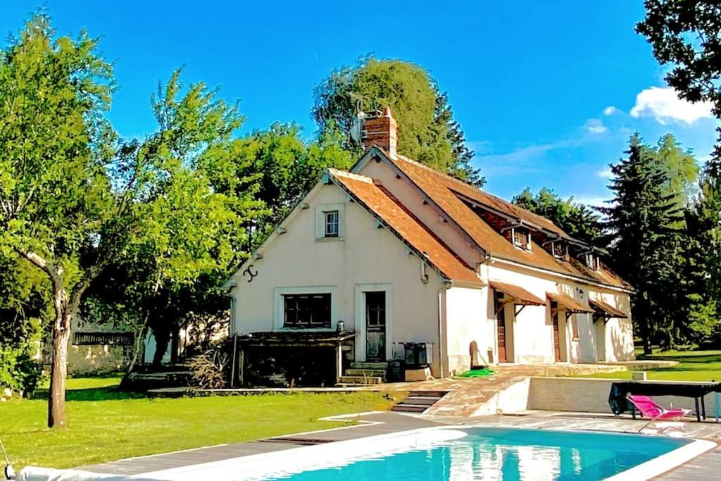 uma casa com uma piscina em frente em Longère normande, parc, piscine. em Montchevrel