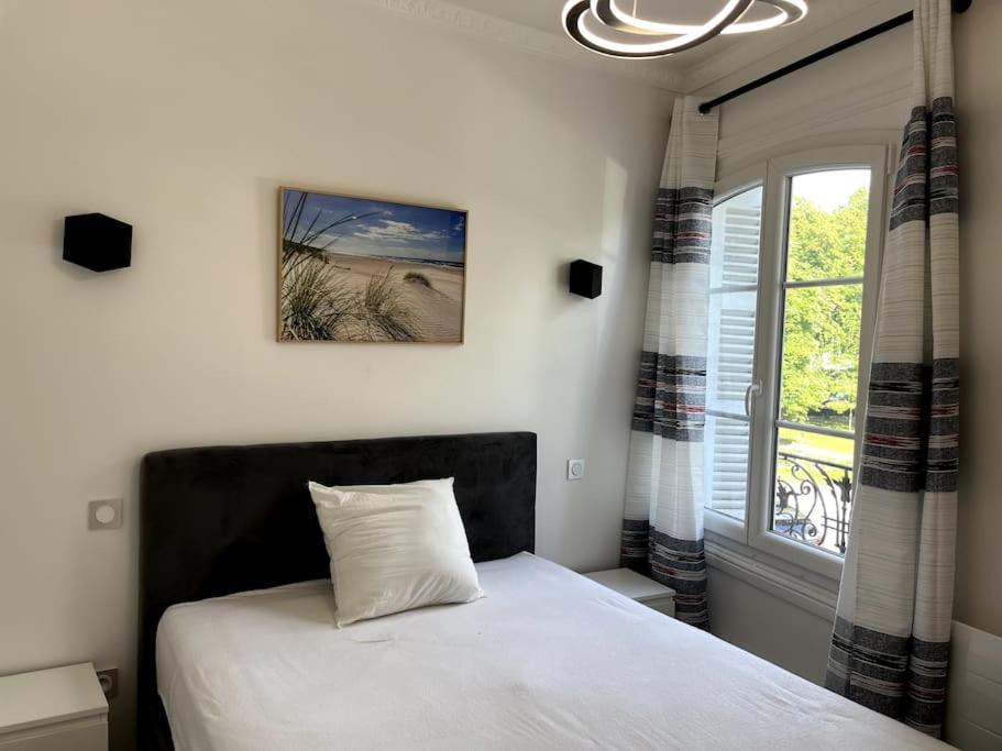 a bedroom with a white bed with a window at Deauville: superbe appartement in Deauville