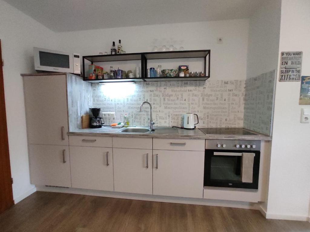 a kitchen with white cabinets and a sink and a microwave at Gästewohnung WaSa in Hamm