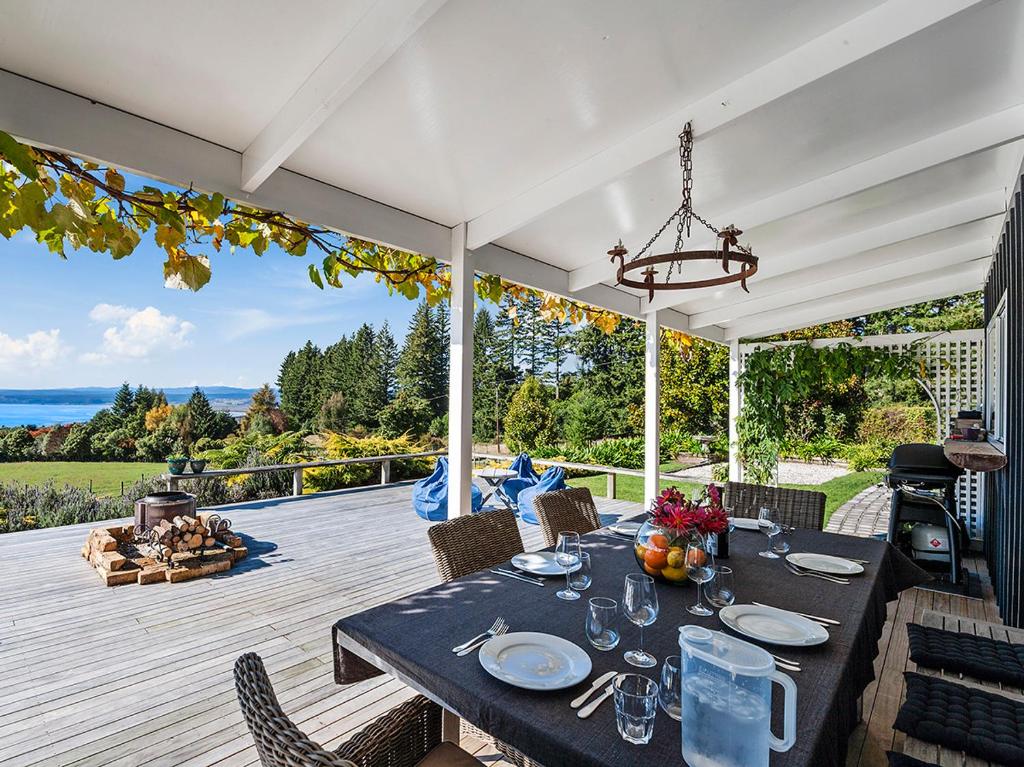 una mesa de comedor en un patio con vistas al océano en Pukawa Country Lodge - Pukawa Bay Holiday Home en Tokaanu
