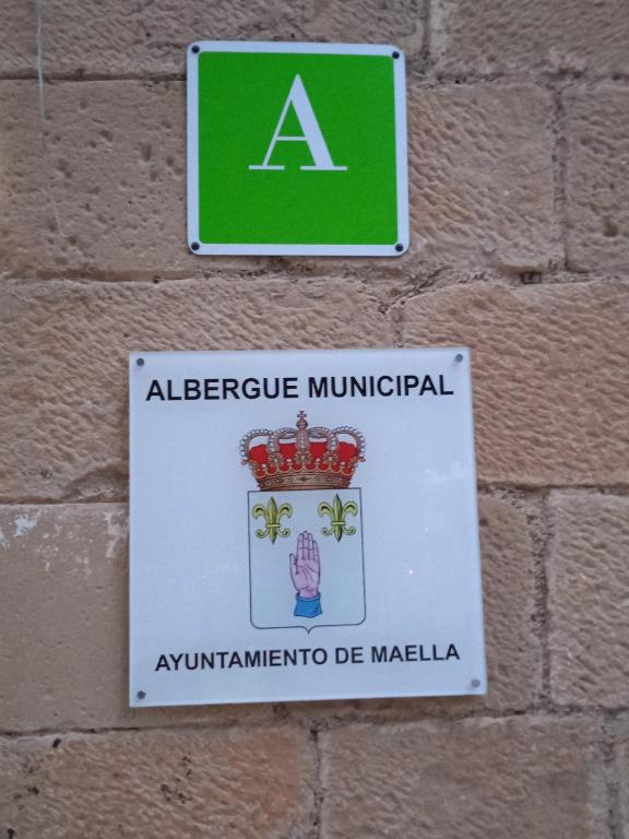 a sign attached to a brick wall at Albergue de Maella in Maella