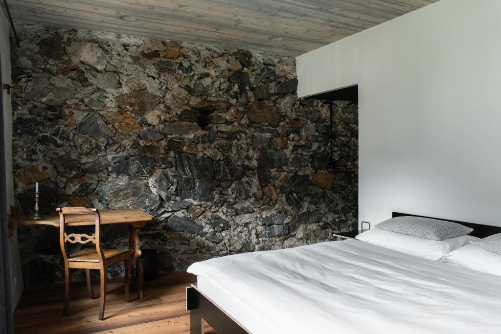 1 dormitorio con 1 cama y 1 mesa con silla en Ein Kraftort und architektonisches Juwel, en Ardez