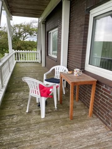 2 Stühle und ein Tisch auf der Veranda eines Hauses in der Unterkunft Wattnest - Ferienwohnung direkt in erster Meereslinie am Deich in Friedrichskoog