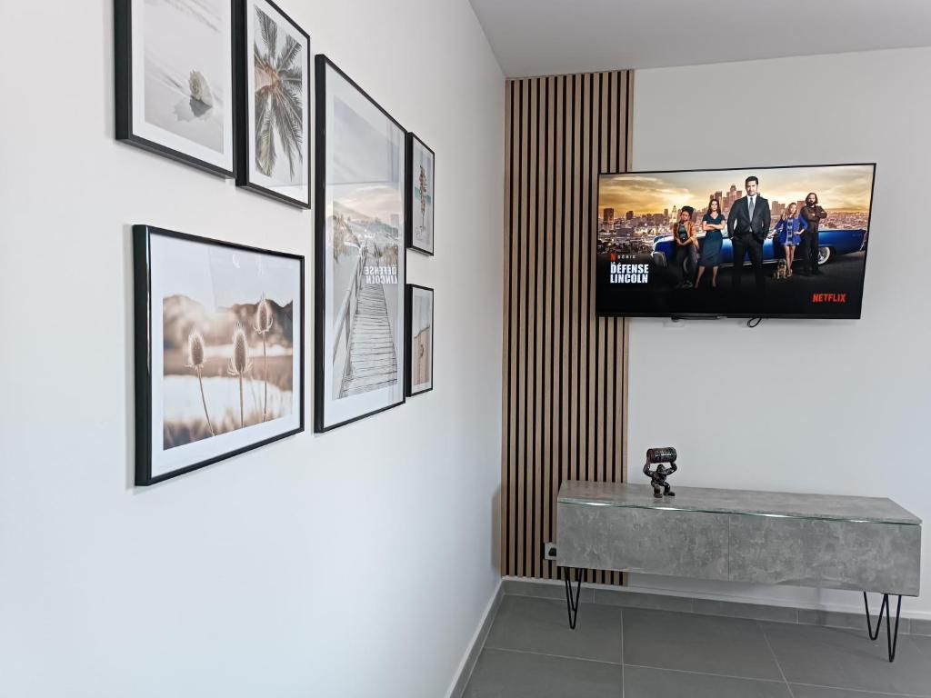 a room with a television on a wall with pictures at Design Therapy in Lavérune