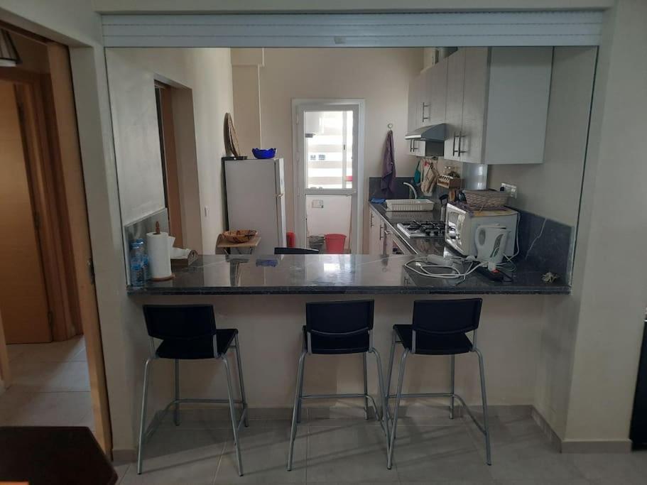 ブズニカにあるAppartement avec piscine à bouznikaのキッチン(バースツール3脚、カウンタートップ付)