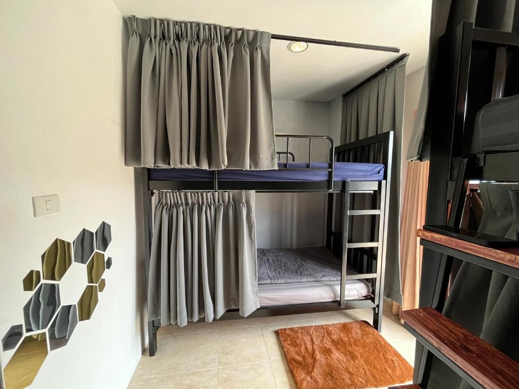 a bunk bed in a room with a curtain at ALPHA Hostel Cafe&Bar in Ban Khlong Yai