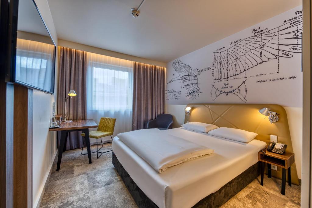 ein Hotelzimmer mit einem großen Bett und einem Schreibtisch in der Unterkunft Mercure Hotel Berlin City in Berlin