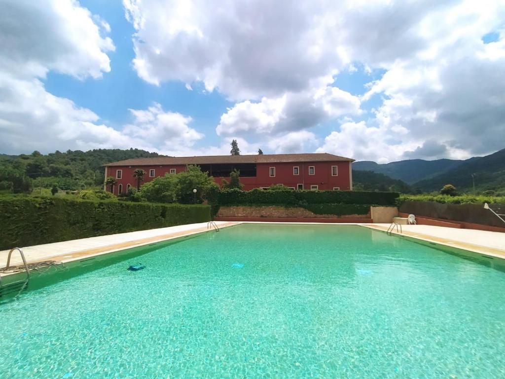 a large swimming pool with a red house in the background at L'Espluga de Francolí Xanascat in Espluga de Francolí