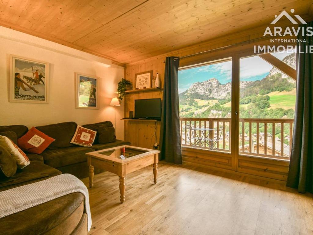 a living room with a couch and a large window at Appartement Le Grand-Bornand, 3 pièces, 4 personnes - FR-1-391-103 in Le Grand-Bornand