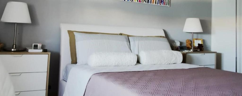 um quarto com uma cama com lençóis brancos e almofadas em DelleArtiGuesthouse Trapani Porto em Trapani
