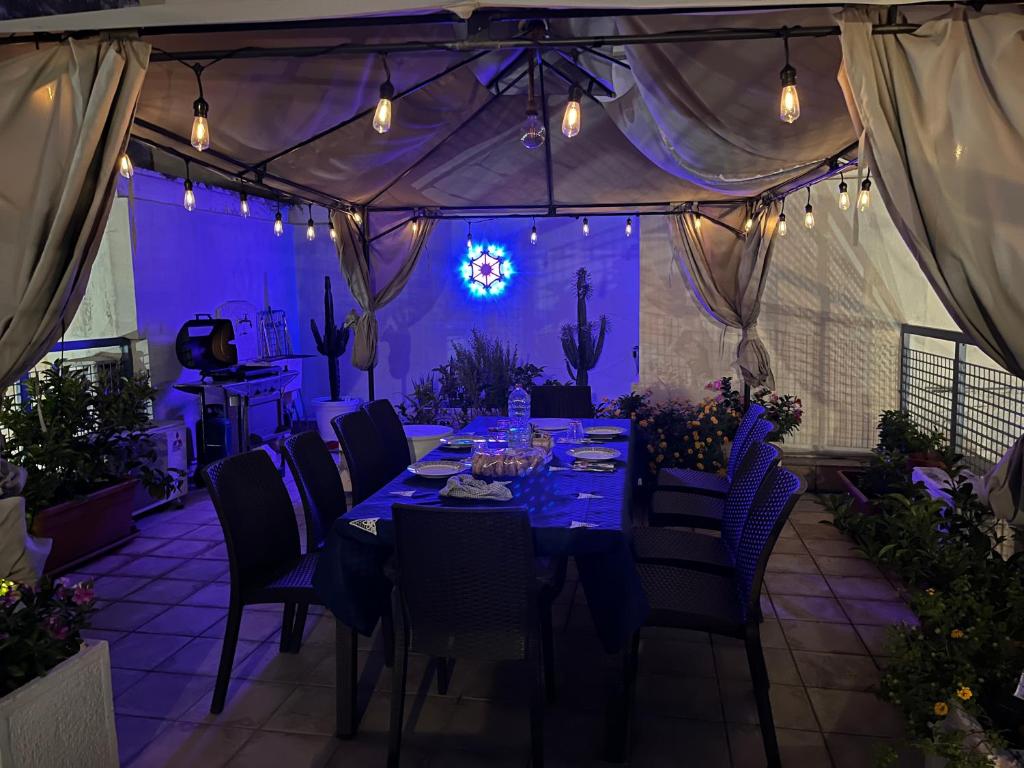 Una mesa larga en una carpa con mesas y sillas azules. en La portuense, en Castro di Lecce