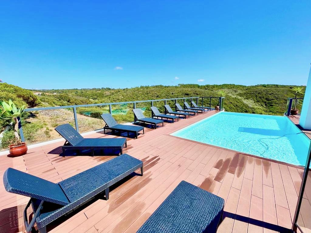 una terraza con tumbonas y una piscina en Stunning Coastal Retreat - Two-Bedroom Apartment in Zambujeira do Mar, en Zambujeira do Mar