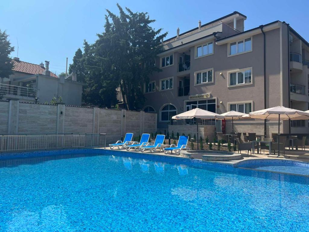 una piscina con sillas y sombrillas junto a un edificio en Vemara City Apart Hotel en Varna