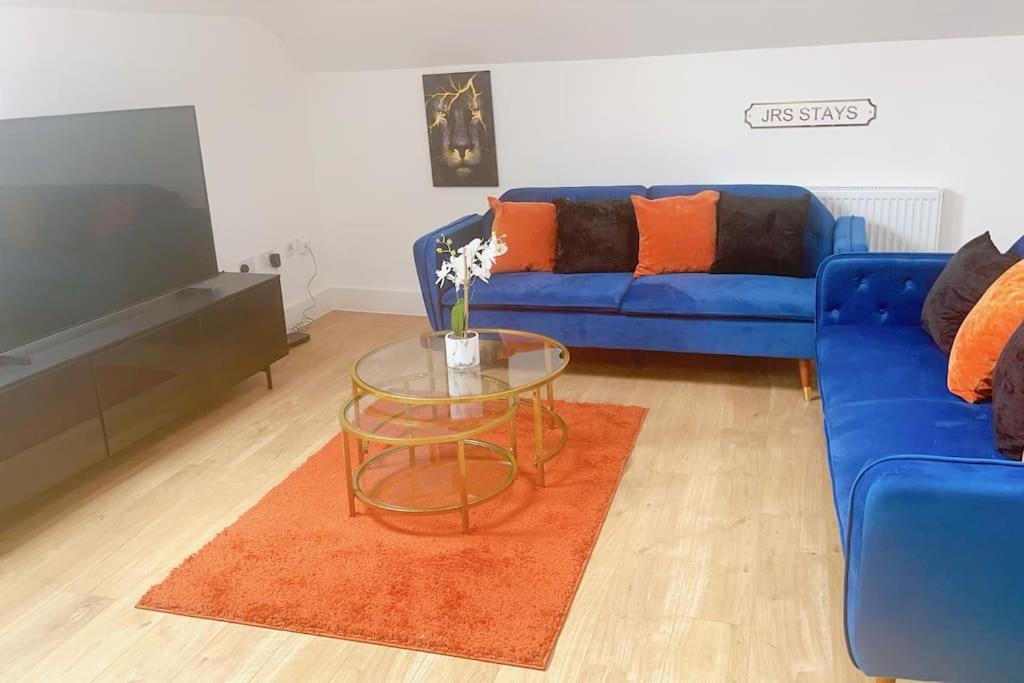 a living room with a blue couch and a glass table at Spacious City Centre Apartment near Lakeside in Stifford