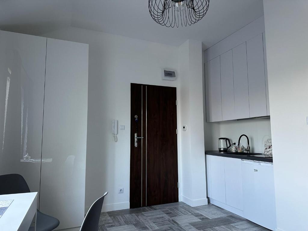 a kitchen with white cabinets and a brown door at HR Noclegi in Wysokie Mazowieckie