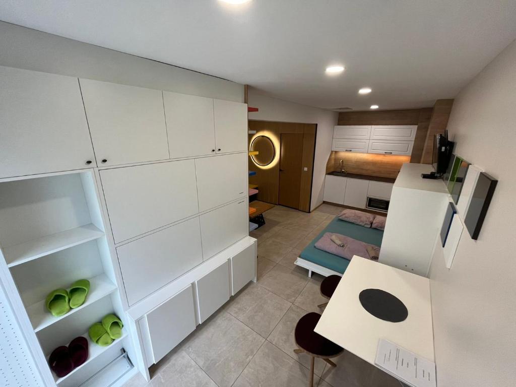 eine Küche mit weißen Schränken, einem Tisch und einem Zimmer in der Unterkunft Apartment ARSO in Velenje