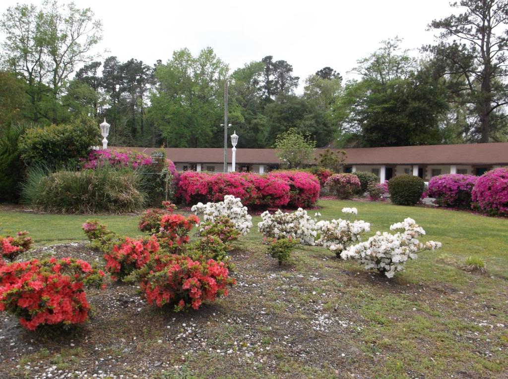 a garden with pink and white flowers in front of a building at Azalea Inn & Suites in Wilmington