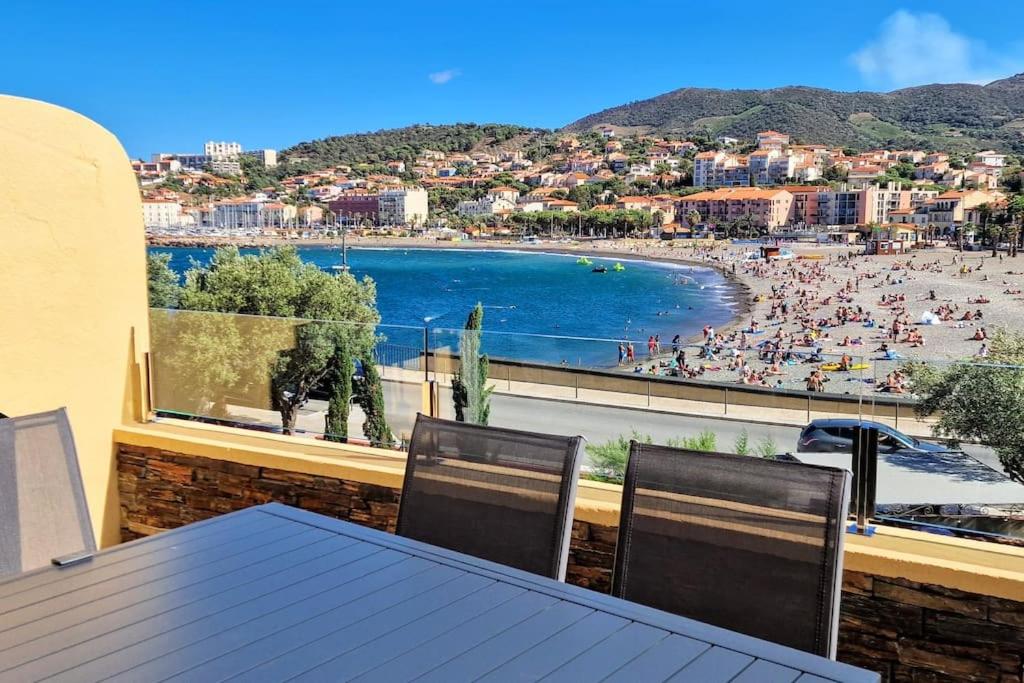 d'un balcon avec une table, des chaises et une plage. dans l'établissement Unique Rare 1ère ligne neuf clim, à Banyuls-sur-Mer