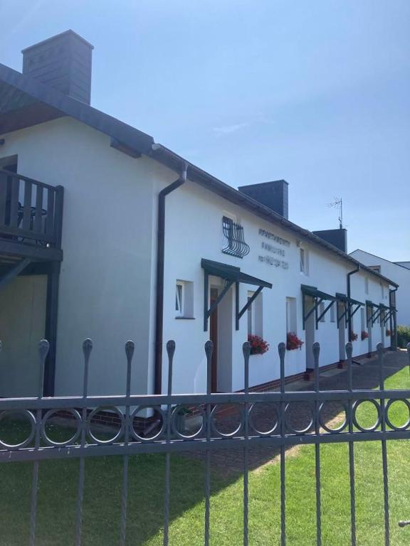 a white building with a fence in front of it at Apartamenty Familijne w Dąbkach in Dąbki