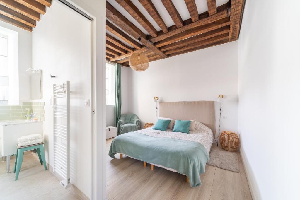 a bedroom with white walls and a bed with blue pillows at Le Clos de la Tour 