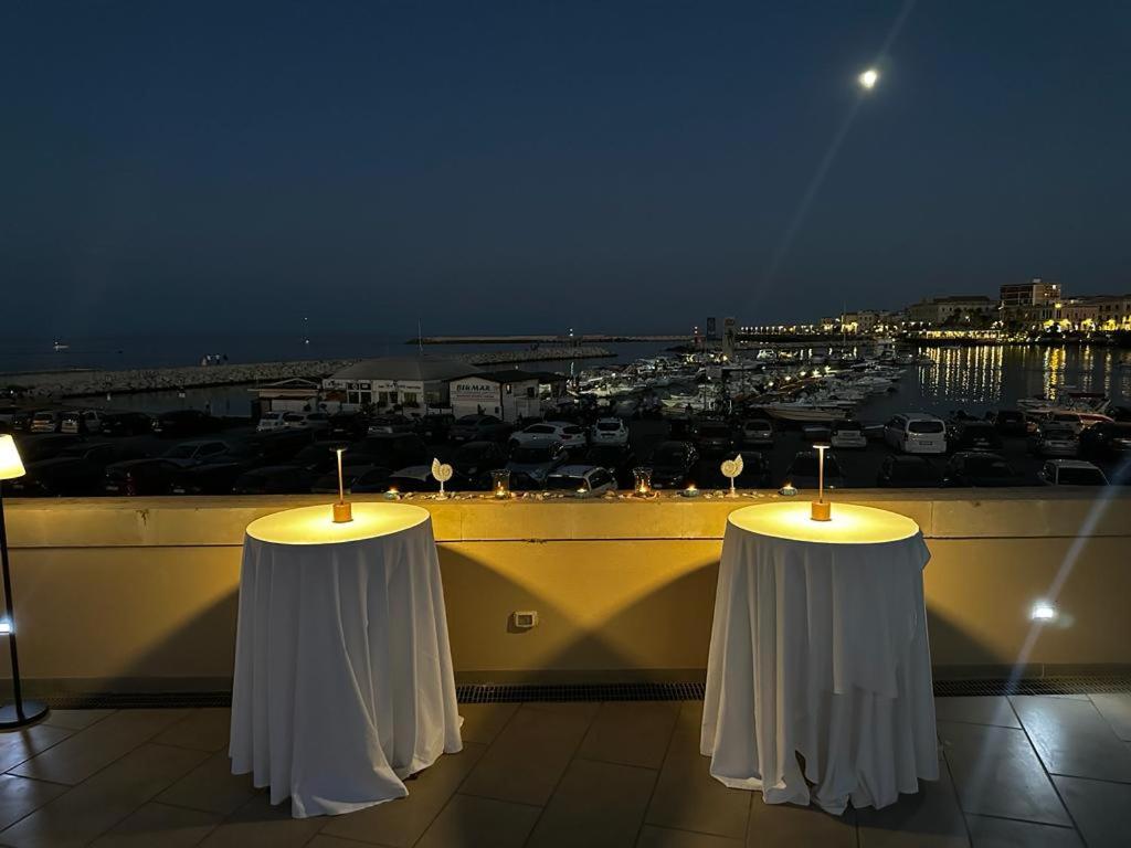 two white tables on a balcony with a view of a city at Boutique Hotel Molo S Lucia in Syracuse