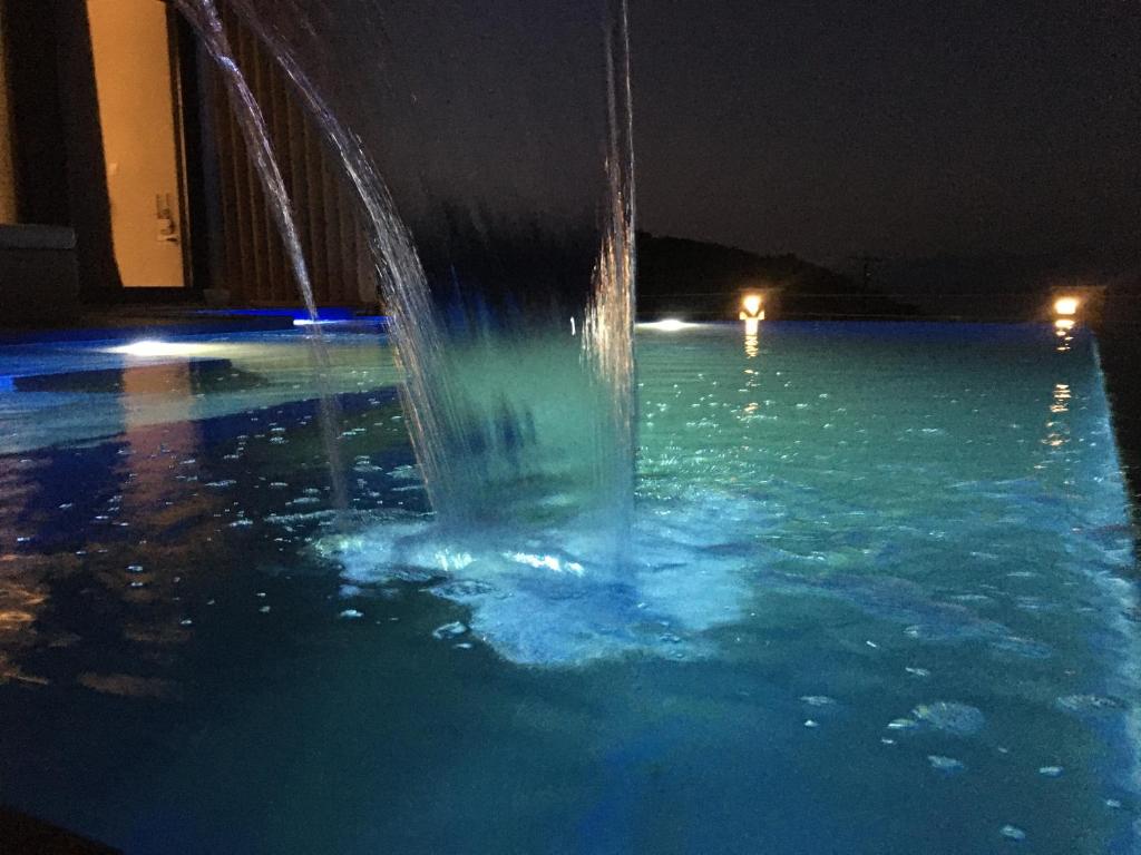 a fountain in a swimming pool at night at The Diamond of Kriaritsi "Villas with private pools & hydromassage" in Kriaritsi