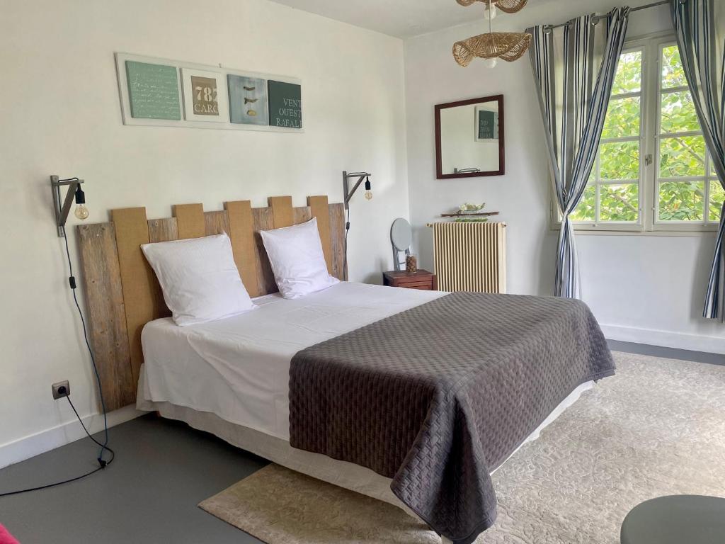 een slaapkamer met een bed met witte lakens en een raam bij Chambres d'Elisa in Saint-Morillon