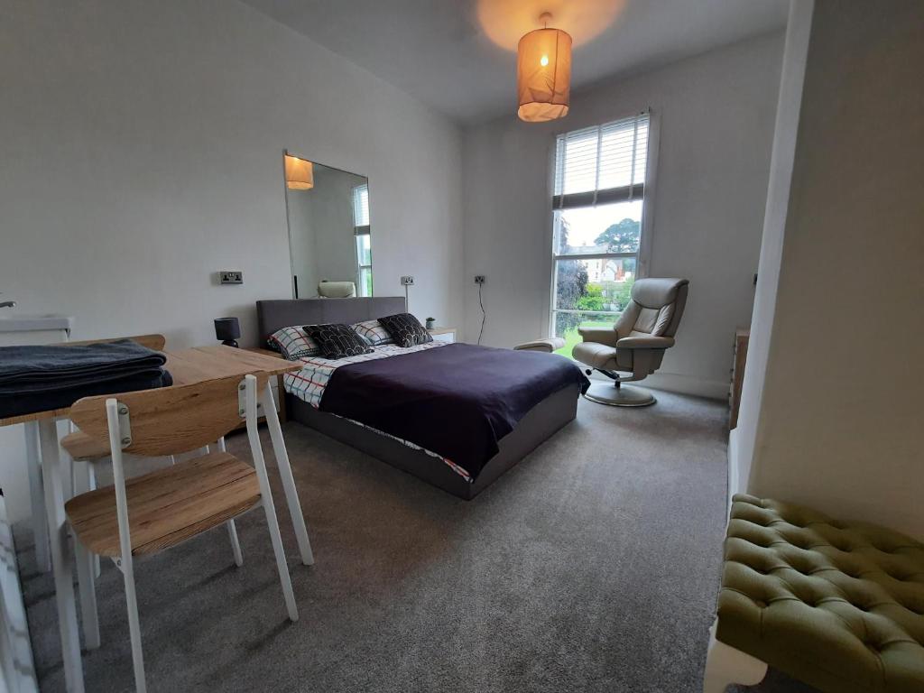 a bedroom with a bed and a desk and a window at Dawlish Lawn View in Dawlish