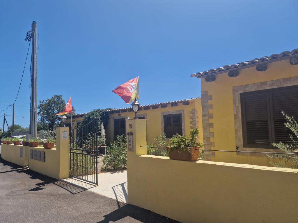 una casa amarilla con una valla y una bandera en Le Case Al Quadrato, en Siracusa