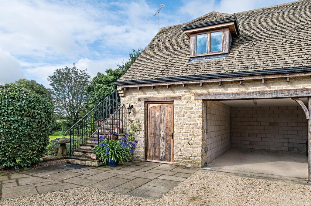 a brick house with a garage and a staircase at Exquisite Coach House Near Silverstone & Stowe in Buckingham