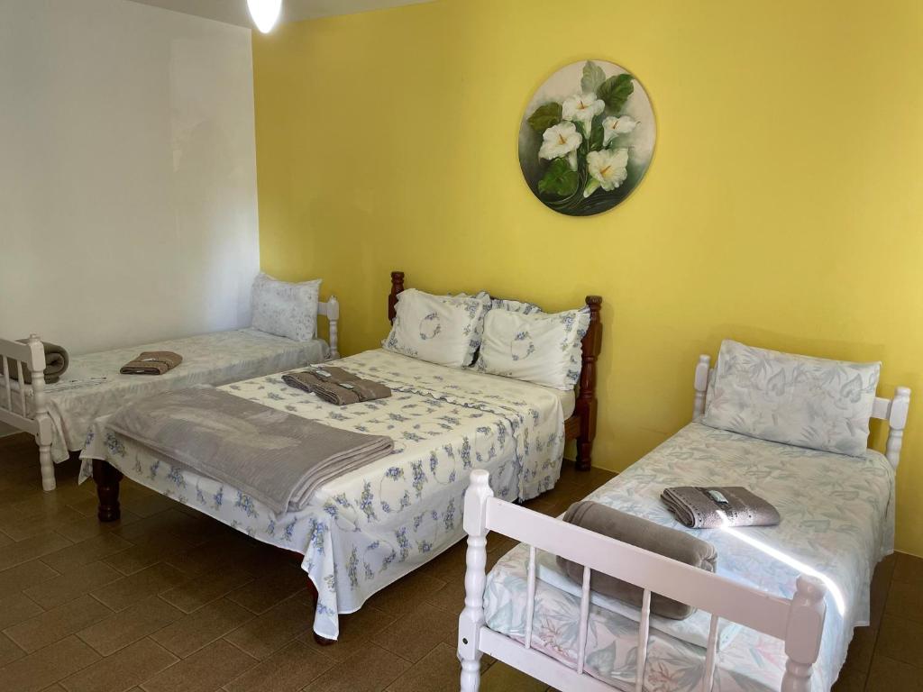 Cette chambre comprend deux lits et une horloge murale. dans l'établissement Pousada Cirandinha, à Itajaí