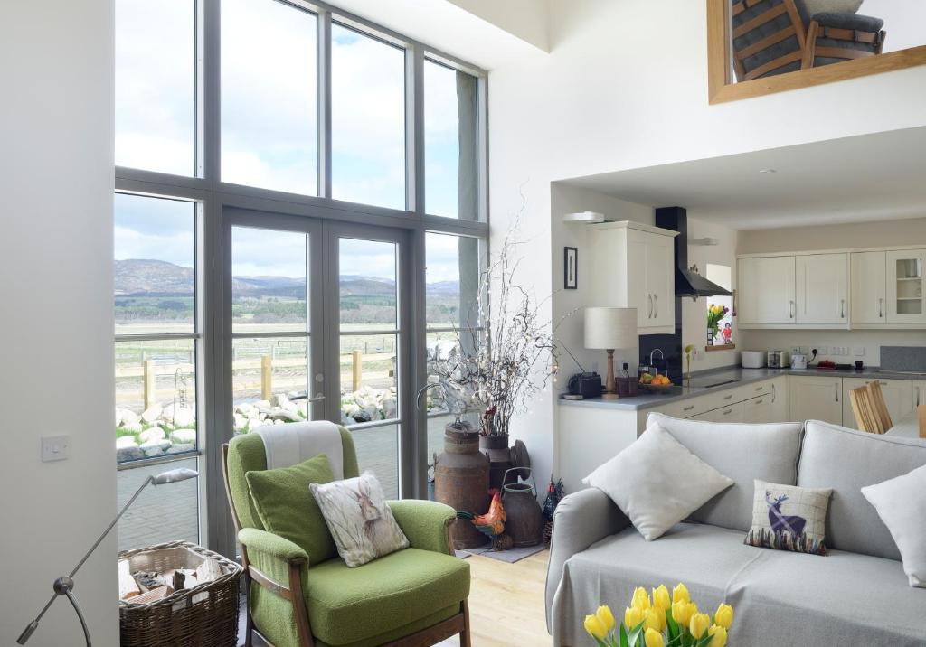 a living room with a couch and two chairs and a kitchen at Osprey Lodge in Kingussie