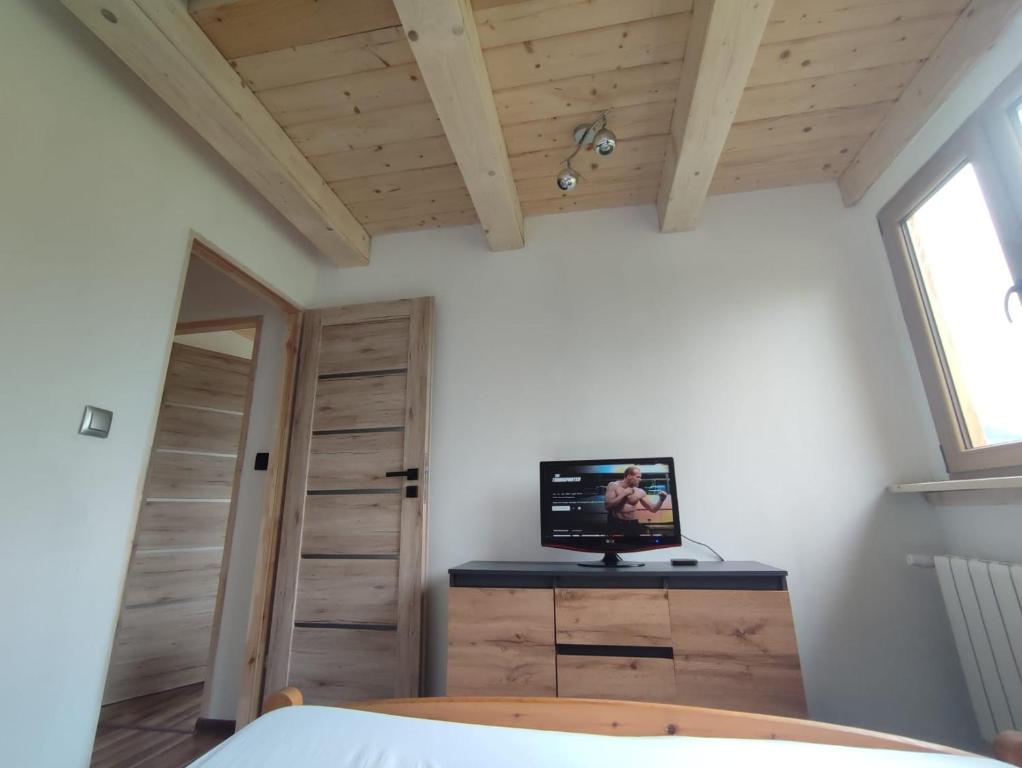 a bedroom with a television on a dresser with a window at Domek u Sołtyska in Rajcza
