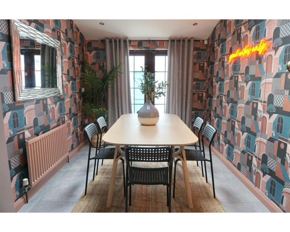 a table and chairs in a room with a wall at Central Belfast Apartments The Village House in Belfast