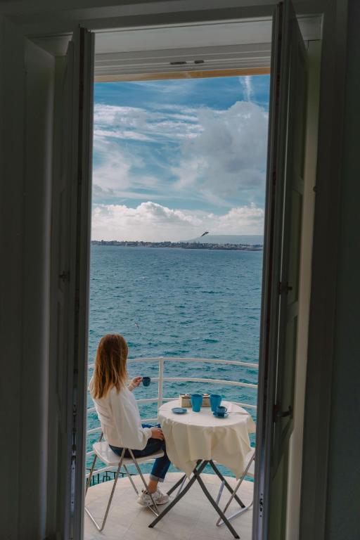 a woman sitting at a table on a boat in the water at Panorama Alfeo in Siracusa