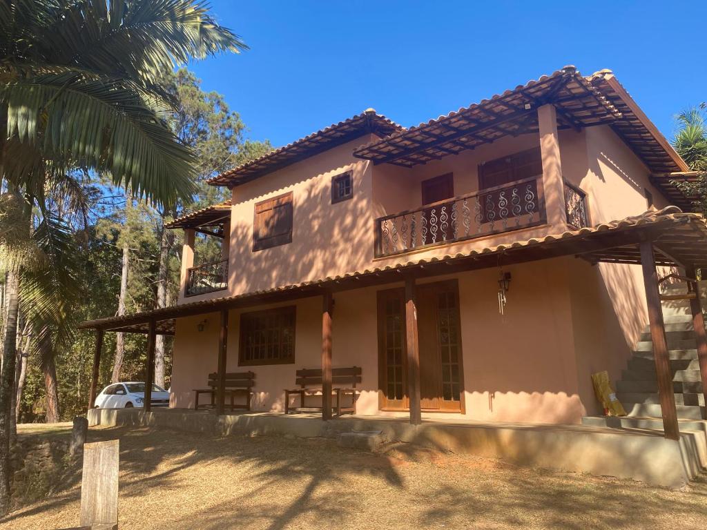 uma casa com uma varanda e uma palmeira em Casa dos Coqueiros - Cama, Café e Eventos em Itabirito